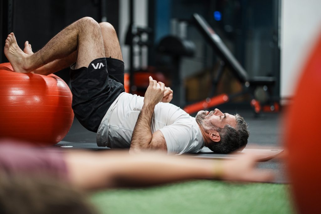 Sommeil et récupération sportive : un client allongé au sol sur un tapis, près d'un swiss ball, pendant un temps de récupération