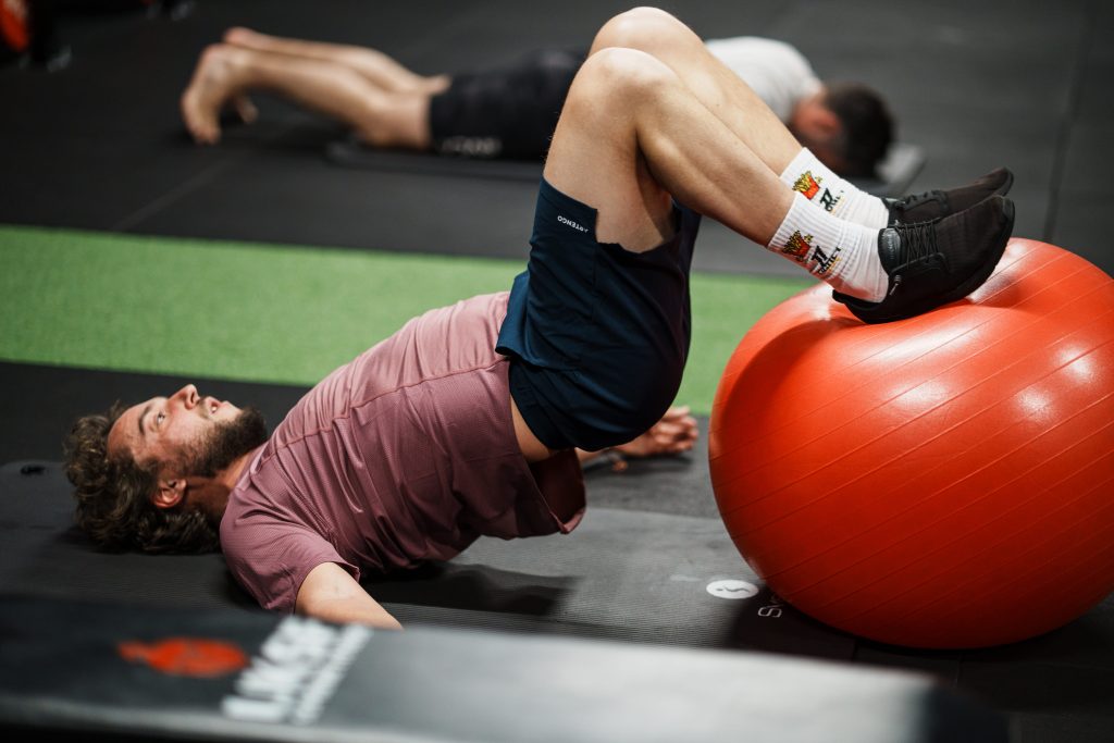 Coaching sportif Bordeaux : un client travaille son gainage et ses fessiers avec un swiss ball pendant sa séance