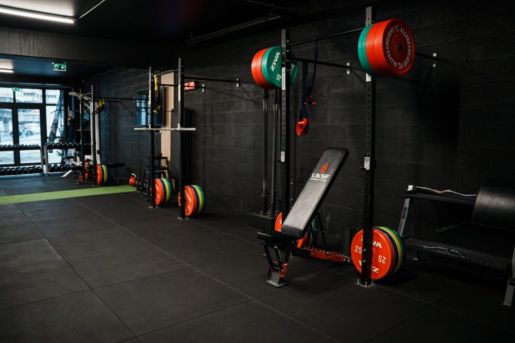 Espace d'entraînement du centre Ultimate Physical à Bordeaux avec racks, barres et disques de musculation
