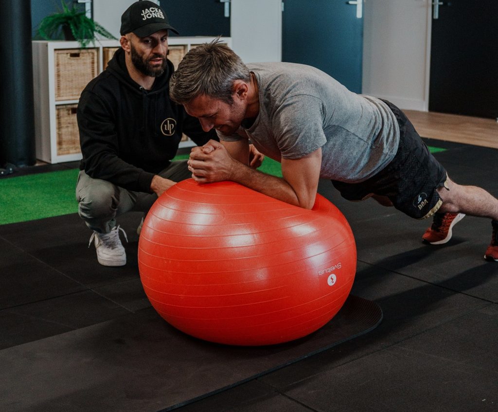 Coach sportif à Pessac et à Mérignac : un coach encadre un client en gainage sur un swiss ball
