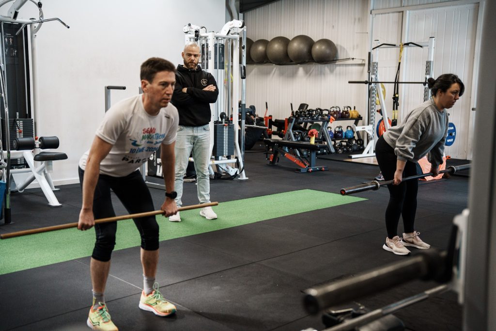 Coach sportif observant la technique de deux clients pendant une séance de coaching sportif personnalisé chez Ultimate Physical