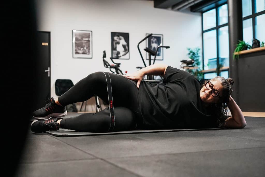 Coaching sportif Bordeaux : une cliente réalise un exercice au sol avec une bande élastique dans le centre Ultimate Physical