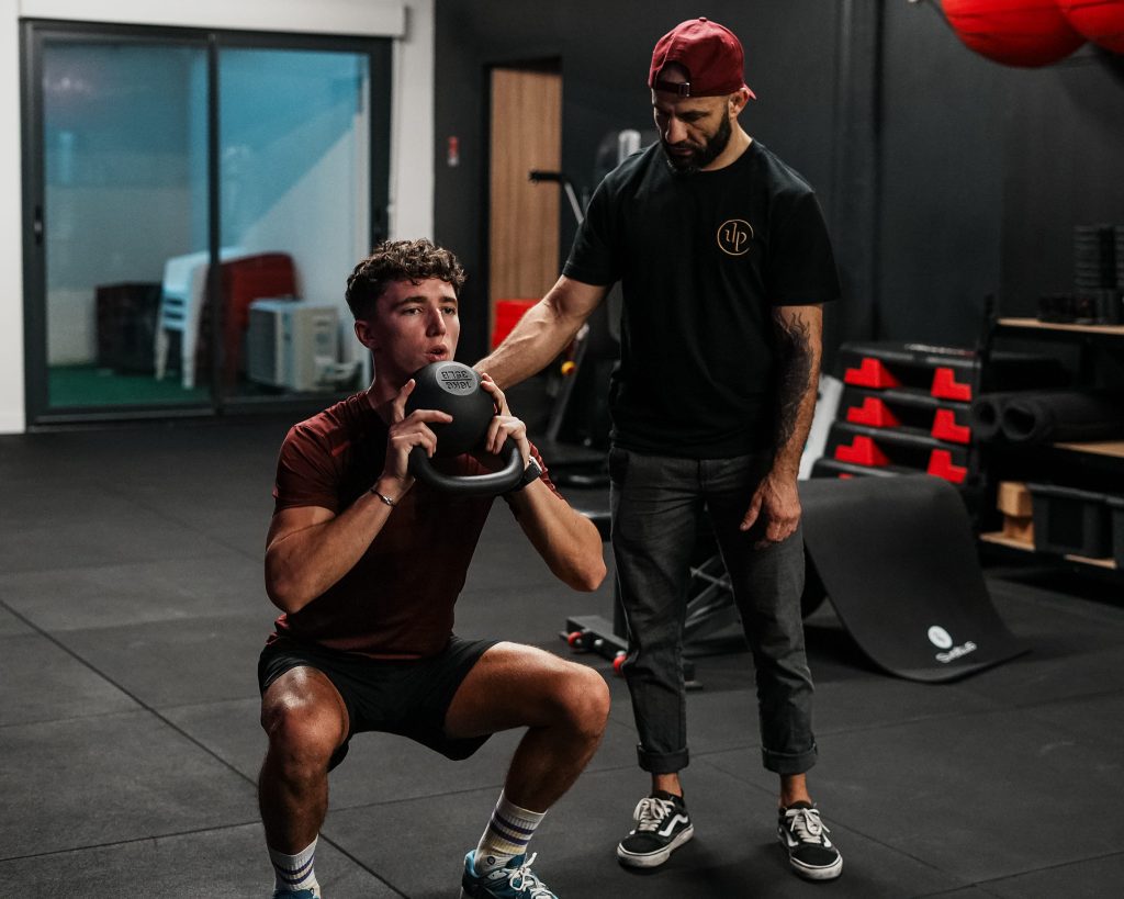 Coach sportif Chartrons et Bordeaux : un coach guide un client pendant un squat avec charge